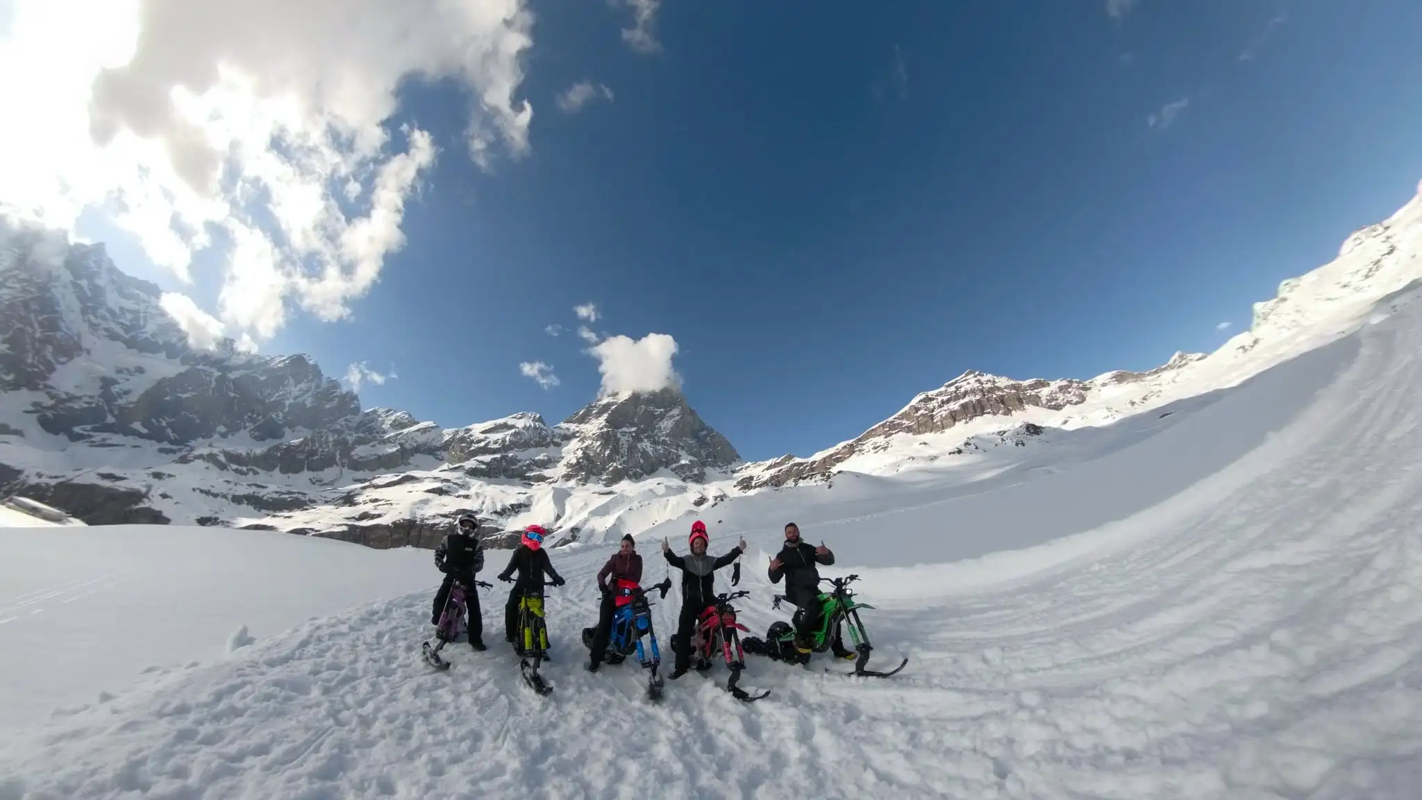 Gruppo con snowbike sotto il sole davanti al Cervino